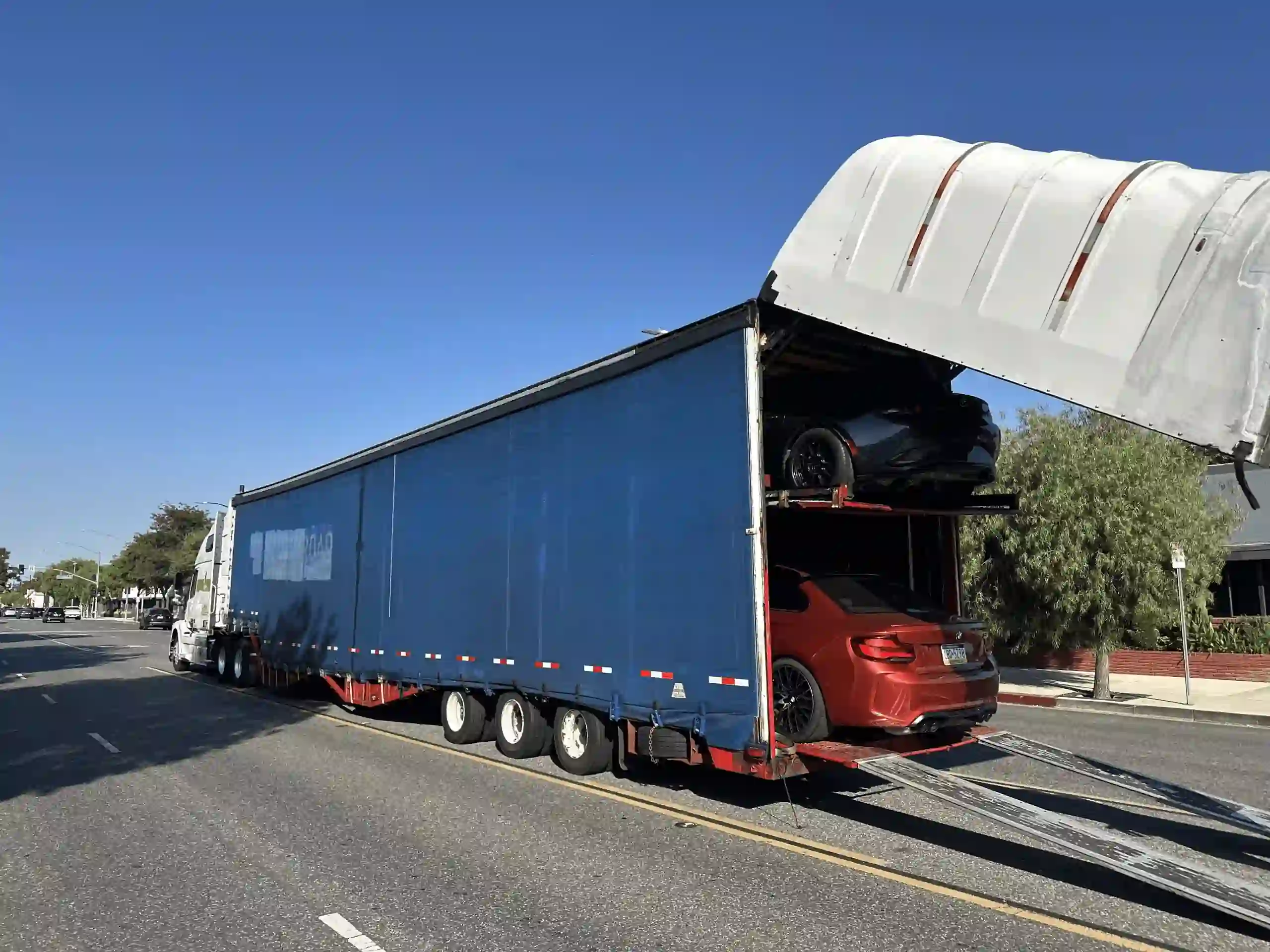 Cars being loaded into an enclosed car carrier trailer